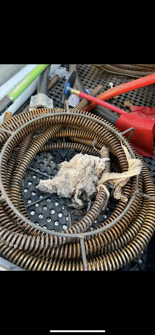 Coiled metal hose with debris in a toolbox.