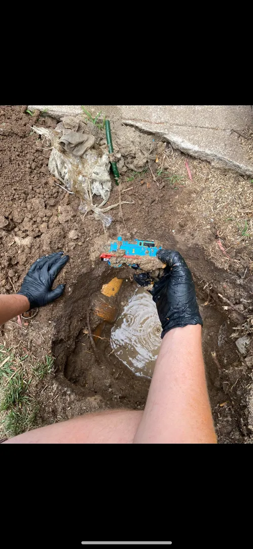 Digging up a toy train from a muddy hole.
