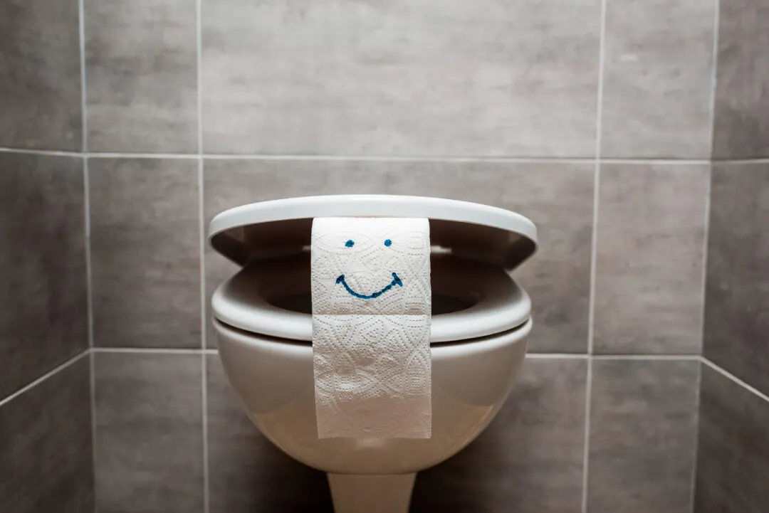 Smiley face on toilet paper in bathroom.